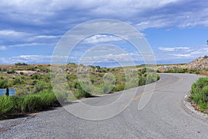 Winding two-lane road with blue sky and drifting clouds