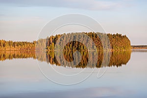 Windless evening at the lake with island reflection on water surface. Karelia, Russia. Horizontal image