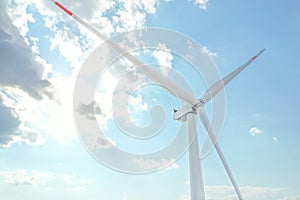 Windmill against sky with clouds, low angle view. Energy efficiency