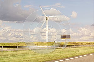 Windmill and billboardin in the field near the road