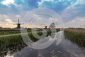 A windmill by a canal in Kinderdijk Holland is reflected in the water