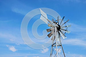 Windmill close up of a and blue sky background. Metal wind turbine with weather vane. Wind energy - old school metal windmill