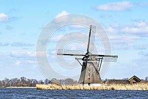 The windmill De Korenmolen along the rough water of lake De Rottemeren on a sunny but stormy day photo
