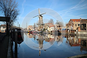 Windmill de Roode Leeuw with reflection in the Turfsingel in Gouda with sails on it.