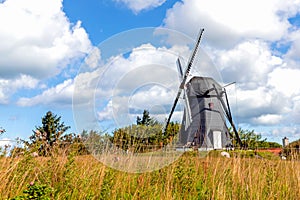 Windmill on a field and blue sky with clouds. Rural landscape