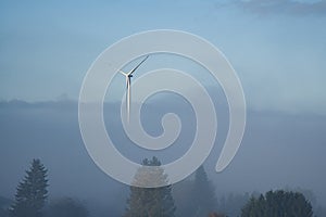 Windmill in foggy landscape. Renewable energy for environmentally conscious future