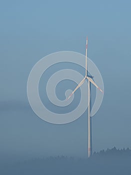 Windmill in foggy landscape. Renewable energy for environmentally conscious future