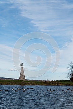 windmill in front of a lake with blue sky background