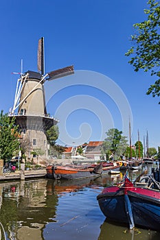 Windmill and historic ships at the canal in Gouda
