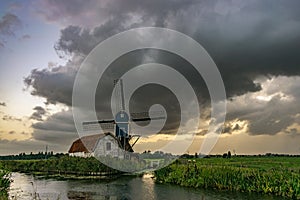 A windmill with house in Holland under a dramatic sky