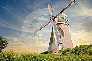 Windmill located on a field in the sunset
