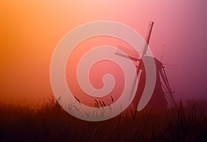 Windmill in the mist. A windmill rises from a misty field