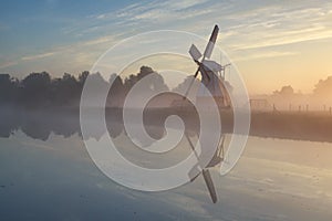 Windmill in morning sunshine reflected in river