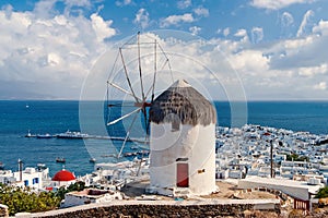 Windmill on mountain by sea in Mykonos, Greece. Windmill on seascape on cloudy sky. White building with sail and straw