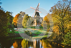 Windmill in a park with many trees and a river. Very colorful postcard