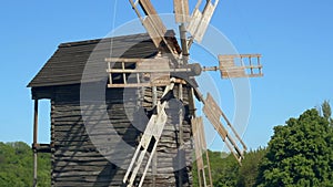 Windmill rotating on wind. Closeup of old mill on blue sky