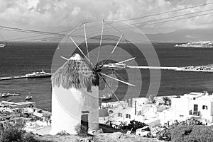 Windmill on seascape in Mykonos, Greece. Windmill on mountain by sea on sky. Whitewashed building with sail and straw