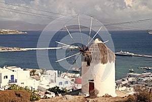 Windmill on seascape in Mykonos, Greece. Windmill on mountain by sea on sky. Whitewashed building with sail and straw