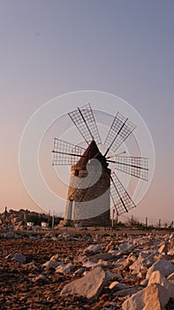 Windmill on the shore seaside with sunset in the background. North of Sicily, Trapani, old fashioned windmill on the