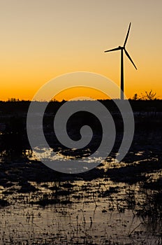 Windmill silhouette in a plain landscape with water reflections