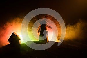 Windmill silhouette standing on hill against the night sky. Night decor with old windmill on hill with horror toned foggy