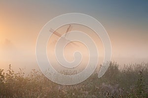 Windmill silhouette in sunrise fog