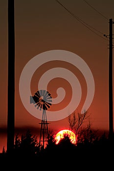 Windmill silhouette at Sunset with a blazing red sky out in the country