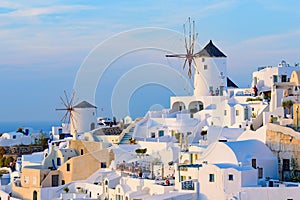 Windmill and traditional white buildings in sunset light in Oia, Santorini, Greece