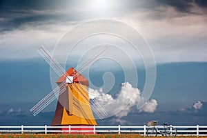 Windmill and vintage bicycle in yellow flower field