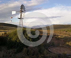 Windmill and water pump in dry landscape