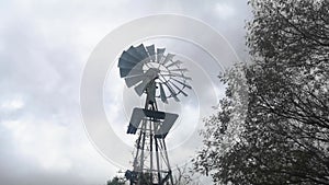 Windmill water pump spinning fast in stormy weather with grey sky