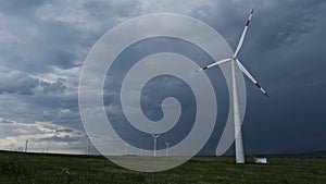Windmill or wind turbine on wind farm in rotation photo