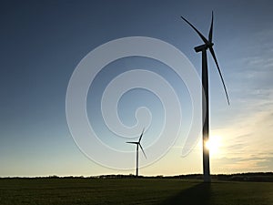 Windmill or wind turbine with the setting sun behind and copyspace