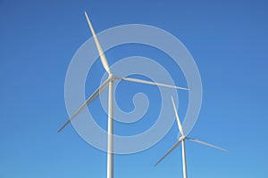 Windmills alternative energy source against clear blue sky background