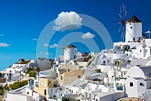 Windmills and cityscape of Oia town on Santorini island in Greece. Traditional white houses. Greece, Aegean Sea. Popular European