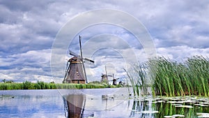 Windmills with dramatic shaped clouds reflected in water, Kinderdijk, Netherlands