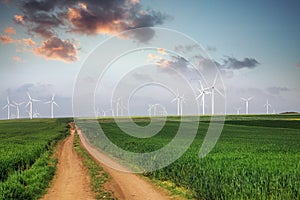 Windmills on the field with Beautiful sundown clouds above Landscape with hills and wind turbines