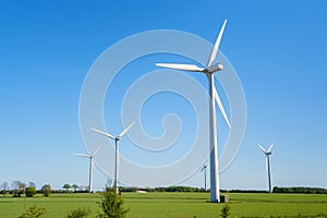 Windmills, Many wind turbines standing on field with lush green grass in spring, alternative energy sources.