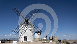 Windmills and old castle in Consuegra, Toledo, Castilla La Mancha, Spain. Several windmills and castle on a hill under a little photo