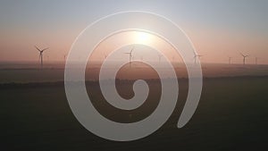 Windmills with rotating wings at sunset or sunrise. Technology for wind energy, renewable energy source, earth care. Wind power