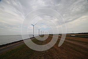 Windmills in a row along a of the IJsselmeer close to lelystat at the Ketelmeer in the Netherlands.