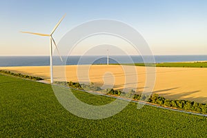 Windmills on the seaside, wind turbine power generators at sunset