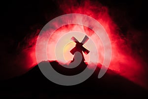 Windmills is silhouette against the night sky. Night decor with old windmill on hill with horror toned foggy background with light