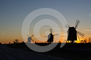Windmills silhouettes by roadside at sunset
