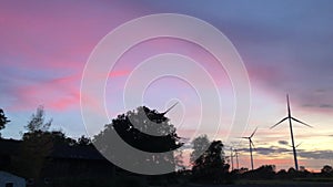 Windmills stand against a colorful background