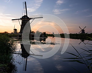 Windmills at sunset reflected in the serene water. Kinderdijk, Netherlands