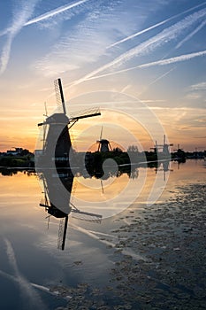 Windmills at sunset reflected in the serene water. Kinderdijk, Netherlands