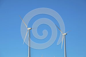 Windmills with three blades against clear blue sky background on a sunny day