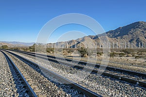 Windmills on a wind park along a railroad track with clear blue sky view