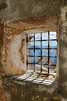 Window on abandoned ruins with rusty bars overlooking Adriatic sea